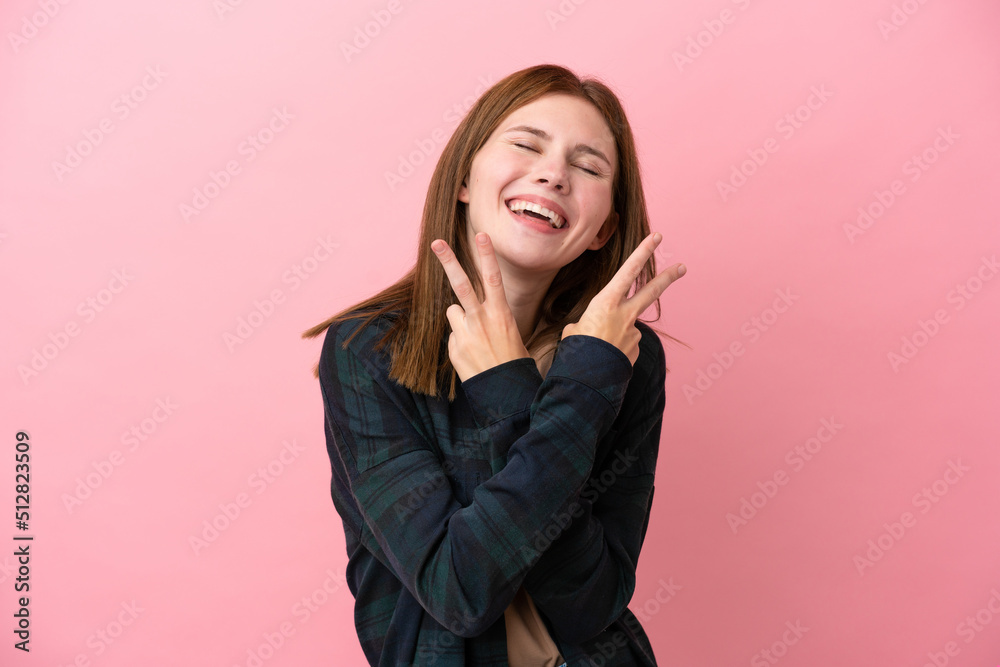 Young English woman isolated on pink background smiling and showing victory sign