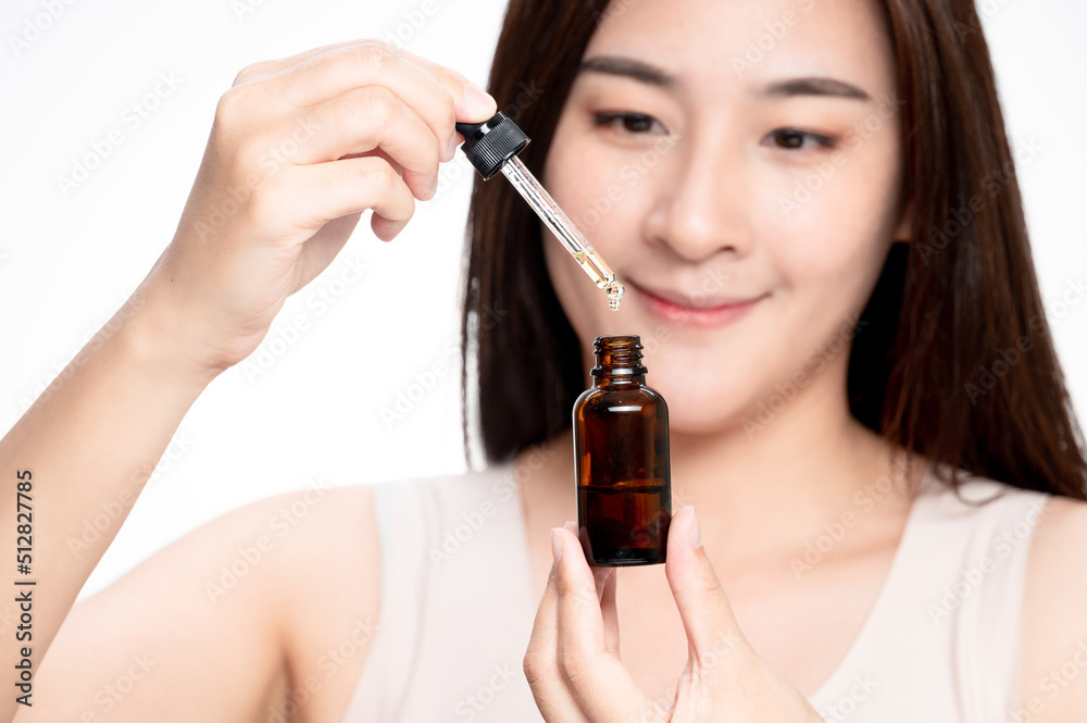 Fototapeta premium Asian woman holding pipette of CBD oil. Close up asian women uses CBD oil for sleep. Medical cannabis. Vitamins and supplements new choice for health.