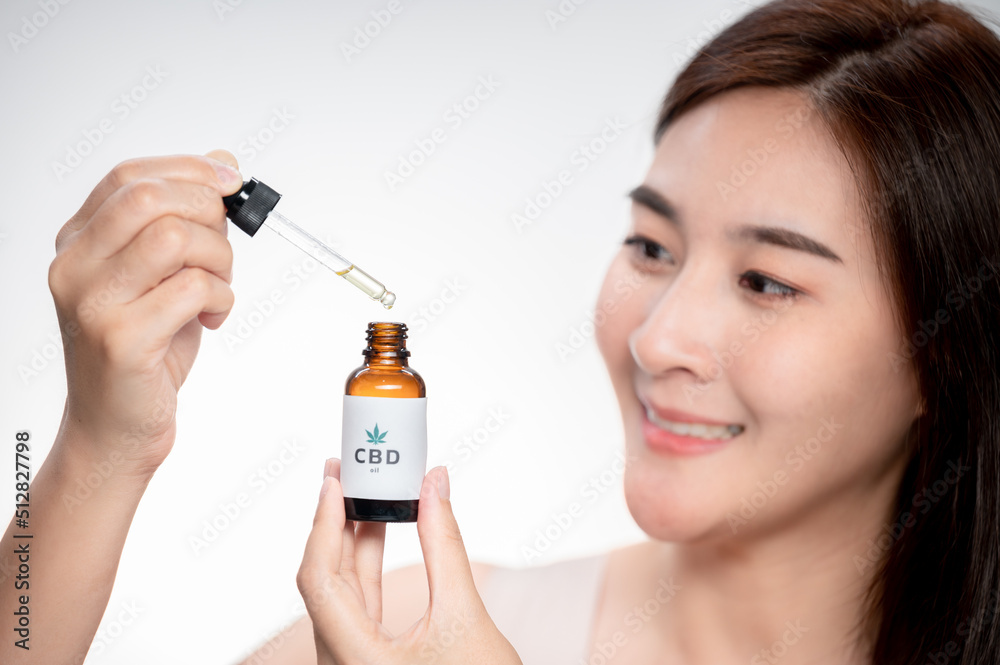 close up asian woman looks at a bottle of CBD oil. Sleep supplement. Medical marijuana. vitamins and supplements healthy alternatives..
