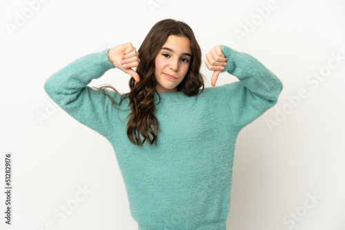 Little caucasian girl isolated on white background showing thumb down with two hands