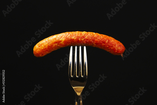 hunting sausage on a fork on a black background. close-up