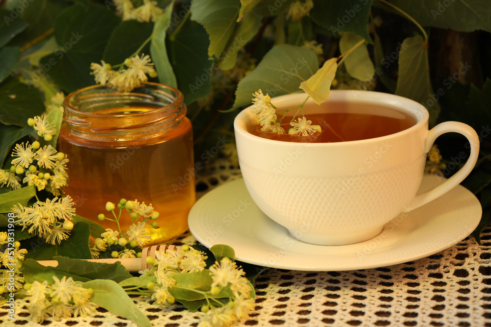 jar of linden honey with linden blossom and cup of tea jar of linden honey with linden blossom and cup of tea