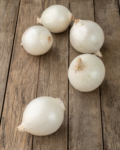 A group of three white onions over wooden table