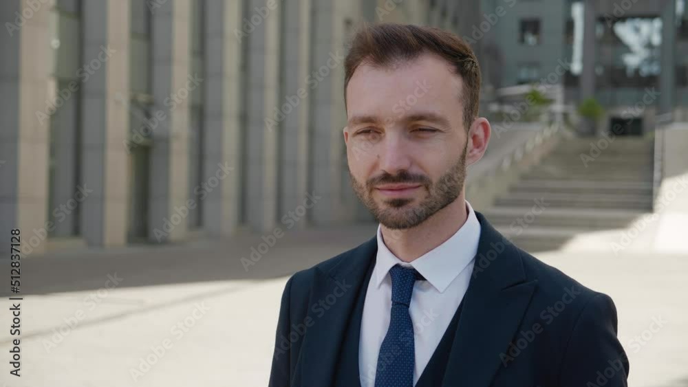 Portrait of smiling ceo executive looking to camera. Male businessman in 30s wearing classical suit posing outdoors on modern office building background Portrait of smiling ceo executive looking to camera. Male businessman in 30s wearing classical suit posing outdoors on modern office building background