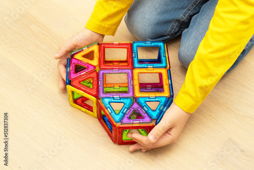 Heart made from magnetic building blocks of construction set in child hands.