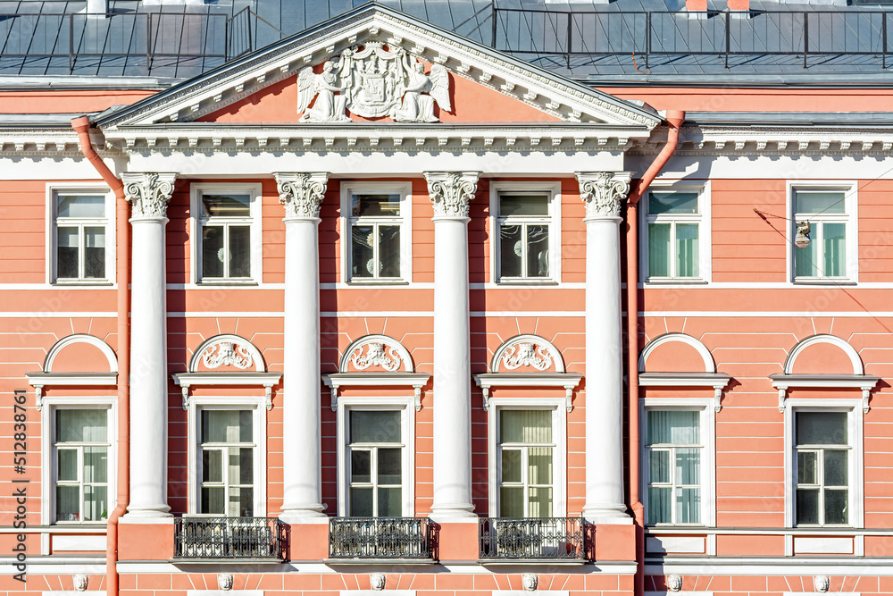 Obraz premium Facade of the building with pink walls with bas-relief, windows, balconies and white columns. From the series windows of St. Petersburg.