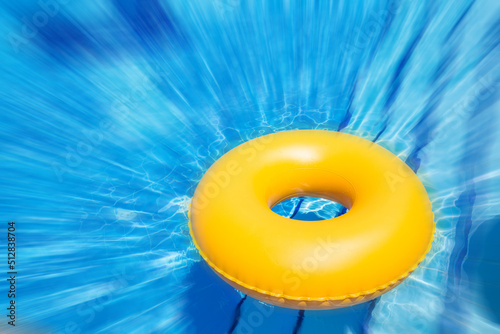 Fotografija inflatable yellow inner tube floating in clear blue waters with motion blur effe