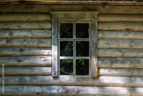 Rectangular window on the wall of a log house, green trees reflected in the glass. From the Window of the World series.