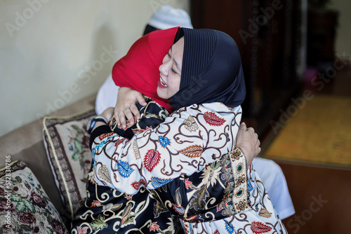 Lebaran homecoming in his hometown greet each other apologizing during the Eid. Family hug each other, mother with daughter. 