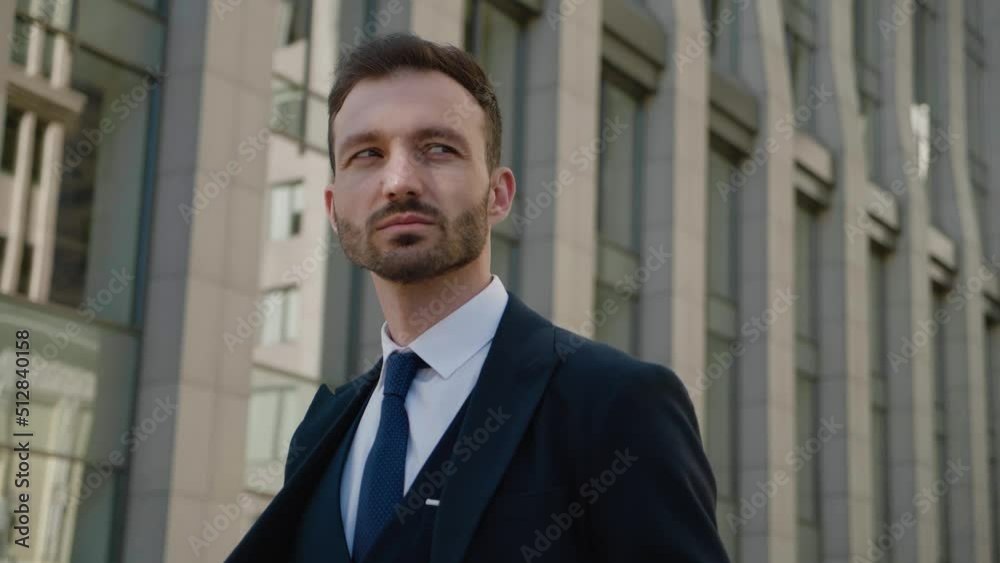 Steadicam shot of confident ceo executive standing at downtown. Man businessman in 30s wearing classical suit posing outdoors on modern office building background Steadicam shot of confident ceo executive standing at downtown. Man businessman in 30s wearing classical suit posing outdoors on modern office building background