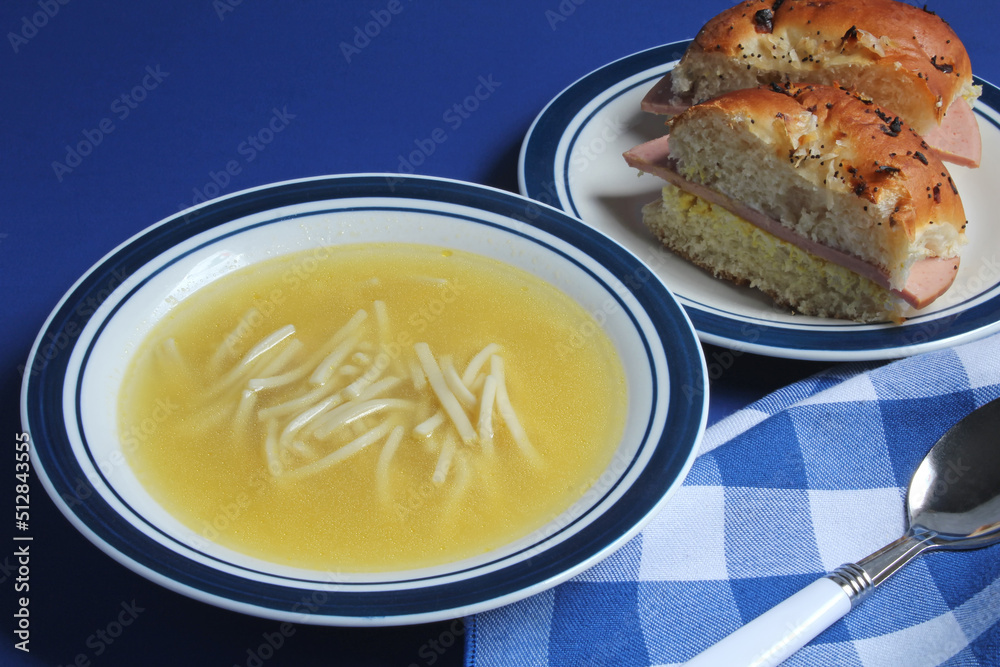 Chicken noodle soup with bologna on an onion bun for lunch. Chicken noodle soup with bologna on an onion bun for lunch.