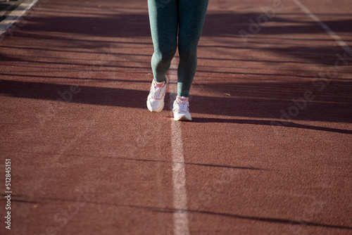 Detalle de pies de mujer corriendo en una pista atlética. Concepto de deportes y gente. © artrolopzimages
