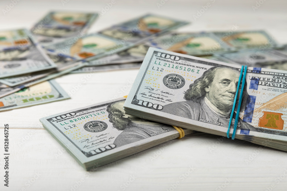 Money, US hundred dollar bills background on white wooden background. Money is scattered on the table. Finance and economics concepts.Money accumulation concept.Currency saving.Investment.Copy space. Money, US hundred dollar bills background on white wooden background. Money is scattered on the table. Finance and economics concepts.Money accumulation concept.Currency saving.Investment.Copy space.