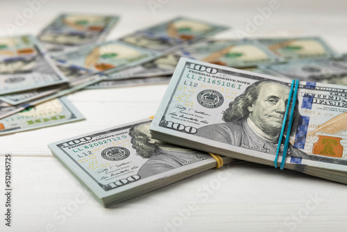 Money, US hundred dollar bills background on white wooden background. Money is scattered on the table. Finance and economics concepts.Money accumulation concept.Currency saving.Investment.Copy space.
