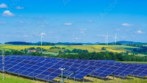 Wind turbines and solar panels in hilly rural area producing green energy