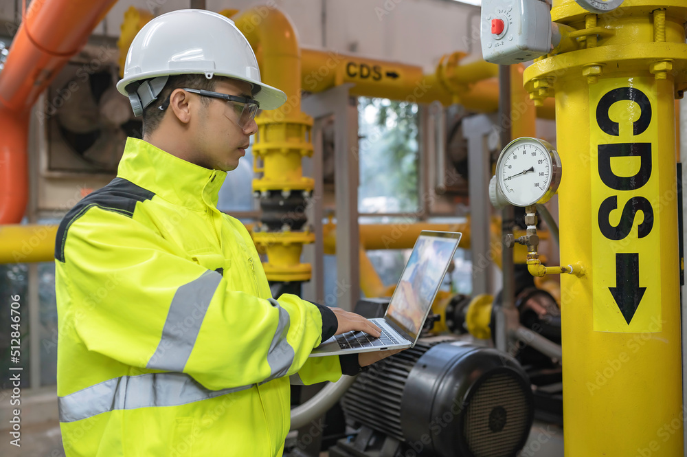 Asian engineer wearing glasses working in the boiler room,maintenance checking technical data of heating system equipment,Thailand people Asian engineer wearing glasses working in the boiler room,maintenance checking technical data of heating system equipment,Thailand people