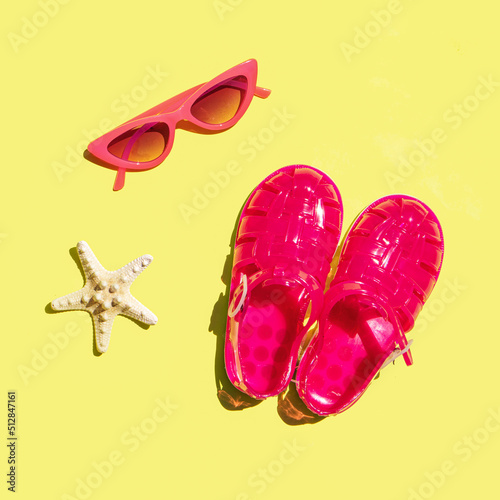 Creative holiday concept. Jelly sandals, sunglasses and starfish on yellow background. Minimal summer composition.