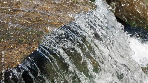 Fast flowing water in the mountain river, water spray from the waves. Texture of seething water, a cascade of a mountain river, bubbles and foam in a stream of water.