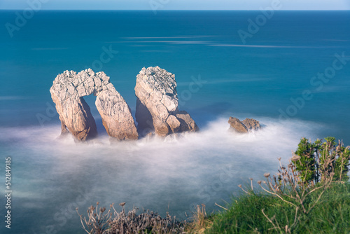 Long exposure view of a beautiful seascape of the spectacular rock formations near the coast in the Cantabrian sea from the cliff edge, Urro in Costa Quebrada, Liencres, Cantabria, Spain photo