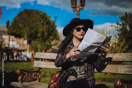 Mujer sentada en un parque revisando un mapa. Concepto de vacaciones y viajes. photo