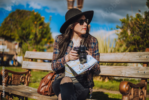 Mujer sentada  mirando su cámara fotográfica con un mapa en la mano. Concepto de vacaciones y viajes. photo