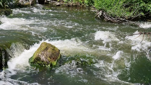 Fast flowing water in the mountain river, water spray from the waves. Texture of seething water, a cascade of a mountain river, bubbles and foam in a stream of water.
