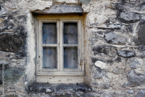Obraz na płótnie Closeup of a wooden frame window on ancient house in a village. Exterior of old dirty window and wall on farmhouse. A small window and grey stone or brick wall of an old antique building or cottage w salonie