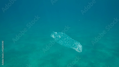 Plastic pollution, plastic bottle in blue water. Discarded plastic bottle slowly drifting under surface of blue water in sunlight. Plastic garbage environmental pollution problem in Ocean. Red sea