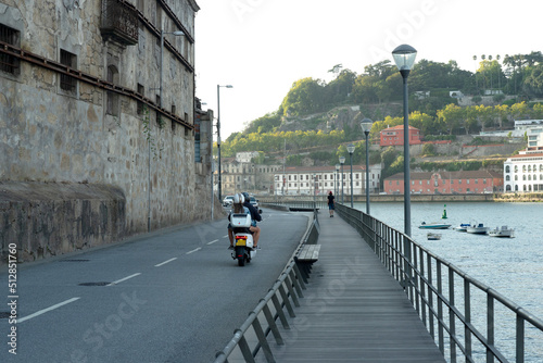 Motorcycles and pedestrians run next to the river, harbour view in the morning