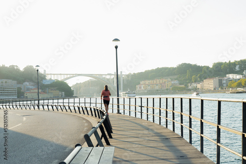 A woman is running along the river on a wooden path