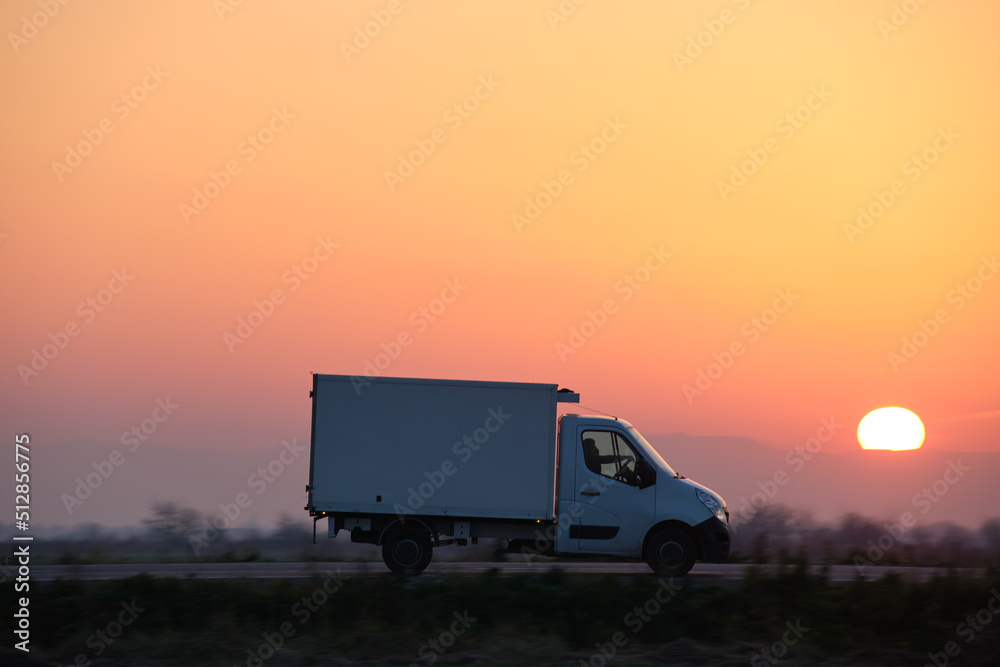 Cargo truck driving on highway hauling goods in evening. Delivery transportation and logistics concept Cargo truck driving on highway hauling goods in evening. Delivery transportation and logistics concept