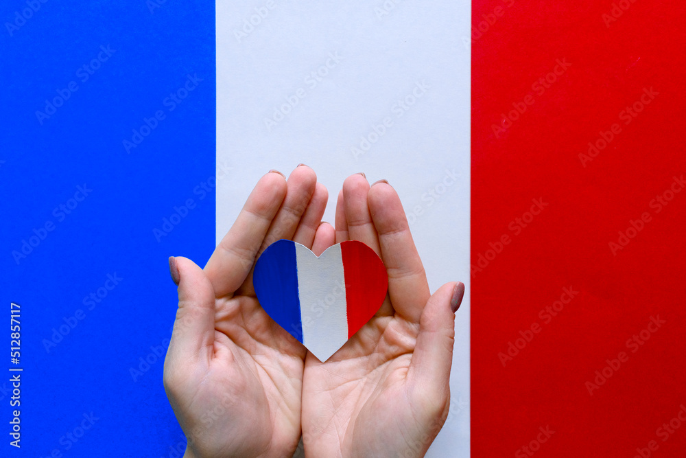 Paper heart in the colors of the flag of France in female hands. Paper heart in the colors of the flag of France in female hands.