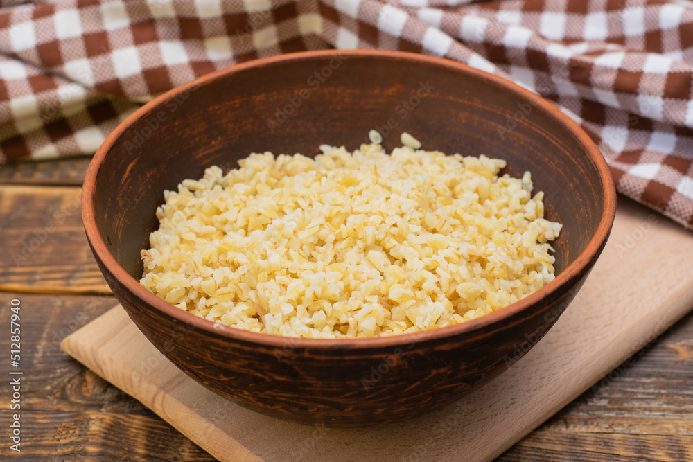 Cooked bulgur porridge in a clay bowl on a wooden table. Bulgur, wheat grains, healthy porridge, vegan food. Cooked bulgur porridge in a clay bowl on a wooden table. Bulgur, wheat grains, healthy porridge, vegan food.