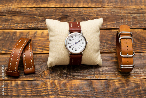 A set of watches and handmade leather straps for them. Stylish, vintage replacement watch straps made of genuine leather and watches on a wooden background.
