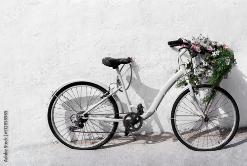 photo of a black and white vintage bicycle with flowers on a white wall