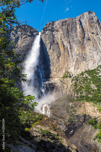 Vertical shot of Upper Yosemite Fall on a beautiful sunny summer day, Epic waterfall under blue sky in Yosemite National Park, California, USA. Natural wonders of the world.