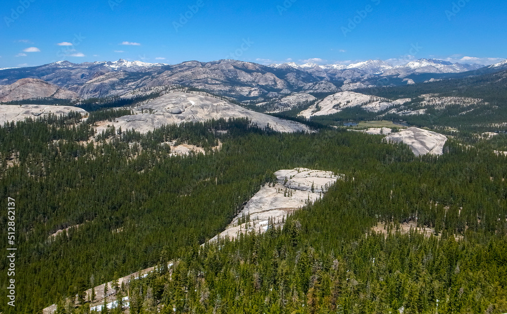 Panoramic shot of Sierra Nevada mountain range in Yosemite National Park, California, USA. Vast landscape with forests and mountain peaks on a beautiful sunny day