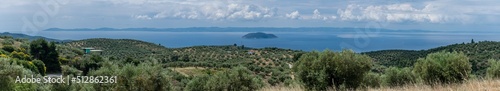 Aerial panoramic view over the Greek seaside with clear blue sky with a small island at sea