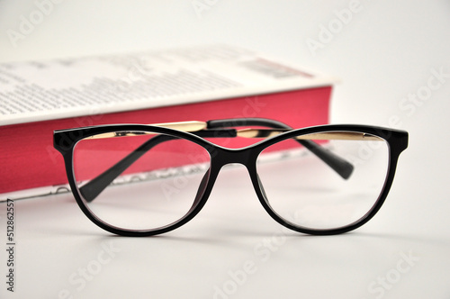 Black Eyeglasses and book on white background.
