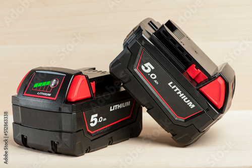 Lithium battery for cordless drill. Screwdriver battery. Four batteries with a charge indicator lie on a wooden background