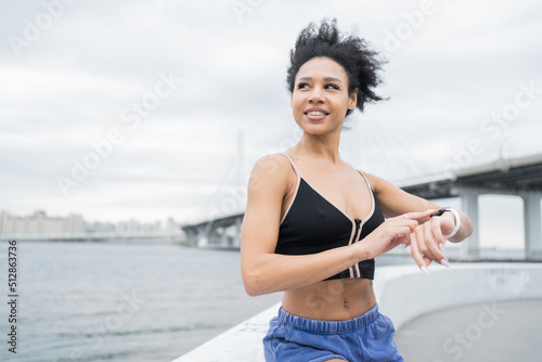 Uses a fitness watch on the arm of a sporty young woman training in sportswear, active exercises for health
