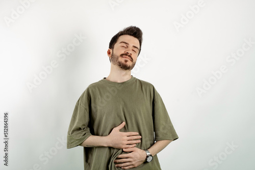 Caucasian man wearing khaki tee posing isolated over white background hand on his stomach after having a meal or a drink. Feeling good.