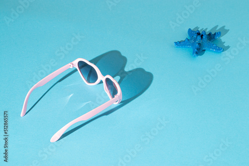Trendy sunny scene with sunglasses and starfish on a blue background. Summer travel concept. Minimal beach idea.