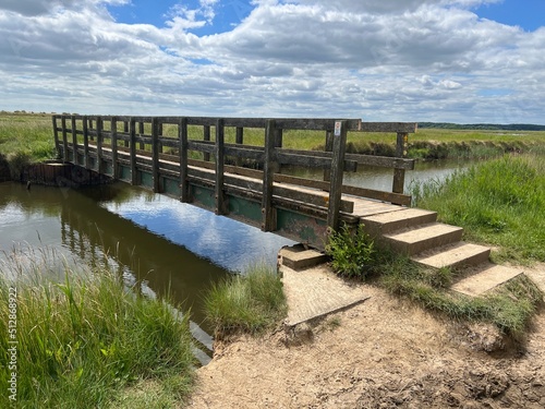 Print op canvas Beautiful landscape with wood bridge over waterway with reeds and sand path at n