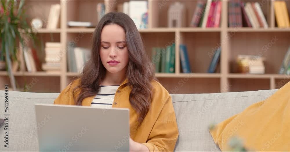 Close up portrait on beautiful caucasian woman sitting on sofa typing on laptop. Woman staring into screen checking social media. Enjoying time during covid 19 concept. Close up portrait on beautiful caucasian woman sitting on sofa typing on laptop. Woman staring into screen checking social media. Enjoying time during covid 19 concept.