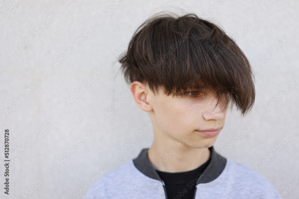 Handsome young man with stylish haircut. Portrait of teen boy with youth hairstyle is standing on grey background. Handsome young man with stylish haircut. Portrait of teen boy with youth hairstyle is standing on grey background.