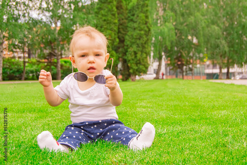 Baby girl sitting on the grass with sunglasses Baby girl sitting on the grass with sunglasses