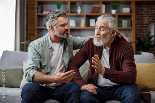 An elderly father complains about life to an adult son, which help him to calm dawn. Two generations family has conversation, sharing news, spending time together. Understanding, care and support photo