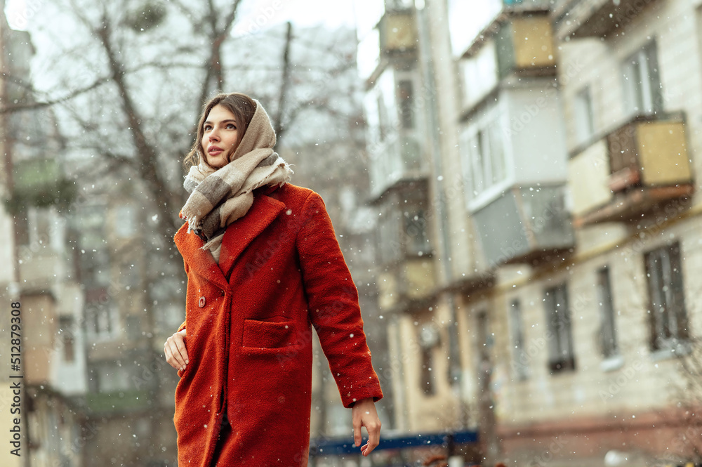 Beautiful brunette in a red coat on a city street under the snow. Beautiful brunette in a red coat on a city street under the snow.