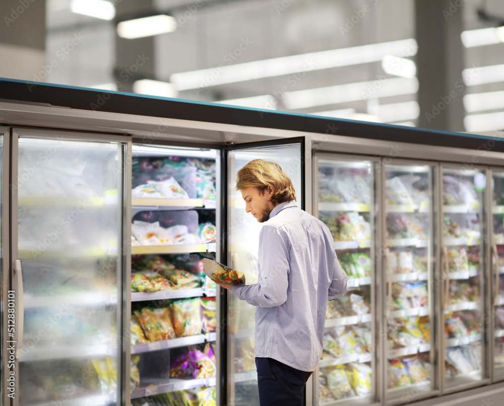 Man choosing frozen food from a supermarket freezer... choosing a dairy products at supermarket, reading product information Man choosing frozen food from a supermarket freezer... choosing a dairy products at supermarket, reading product information